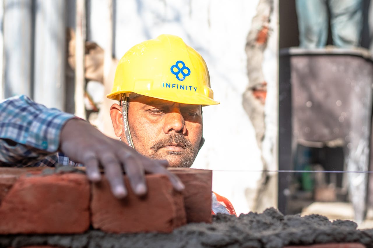 A construction worker carefully aligning bricks on a wall in Delhi, India.